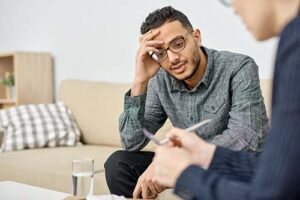 troubled young man talking to his therapist as part of an individual counseling program