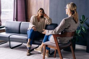 behavioral health specialist and female patient seated in office setting discussing prescription drug addiction treatment.