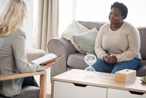 female addiction treatment specialist explaining how long are most IOP programs to a female patient in a pleasant office setting.